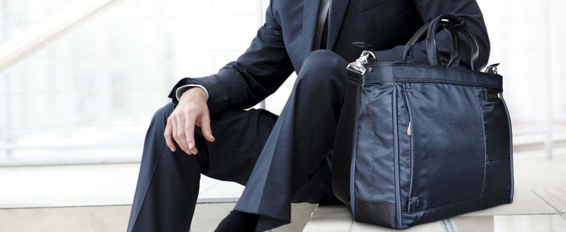 Handsome male business executive sitting on stairs outside a building with his bag